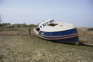 Image showing A small boat in the mud of a river estuary