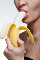 Image showing Young woman biting banana isolated on white