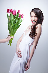 Image showing Smiling woman and hand with bouquet of pink tulips on white