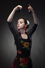 Image showing young woman dancing flamenco with castanets on black