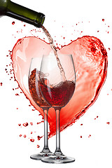 Image showing Red wine pouring into glasses with splash against heart isolated