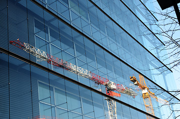 Image showing two cranes are reflected in a glass wall of building