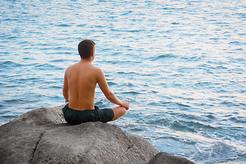 Image showing Man sitting in lotus position and looking at the sea