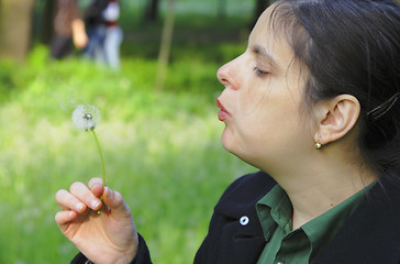 Image showing Woman blowing a dandelion