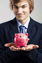 Image showing Holding a piggy bank