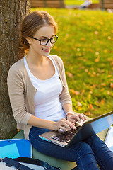 Image showing smiling teenager in eyeglasses with laptop