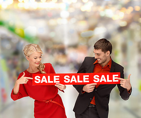 Image showing woman and man pointing finger to red sale sign