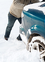 Image showing closeup of man pushing car stuck in snow