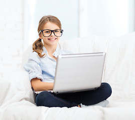 Image showing smiling girl in specs with laptop computer at home