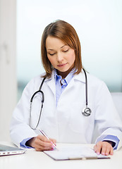 Image showing busy doctor with laptop computer and clipboard