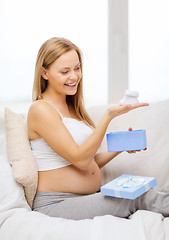 Image showing smiling pregnant woman with gift box and bootees