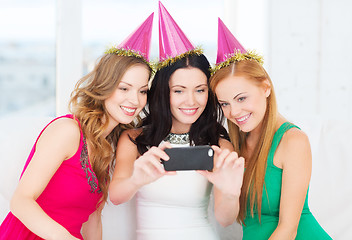 Image showing three smiling women in hats having fun with camera