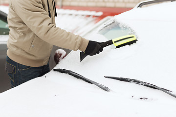 Image showing closeup of man cleaning snow from car