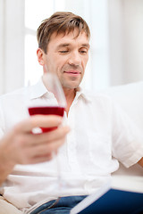 Image showing happy man with book and glass of red wine at home