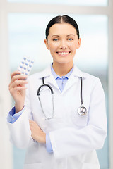 Image showing smiling young doctor with pills and sthethoscope