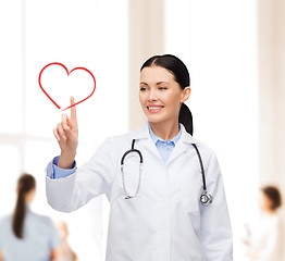 Image showing smiling female doctor pointing to heart