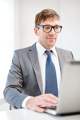 Image showing businessman in eyeglasses with laptop in office