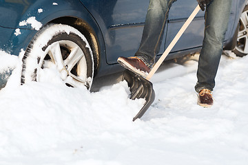 Image showing closeup of man digging up stuck in snow car