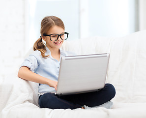 Image showing smiling girl in specs with laptop computer at home