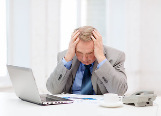 Image showing upset older businessman with laptop and telephone