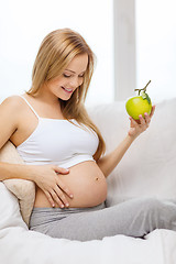 Image showing happy pregnant woman with fresh green apple