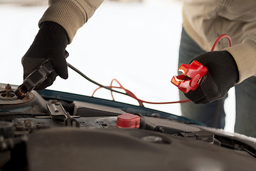 Image showing closeup of man under bonnet with starter cables