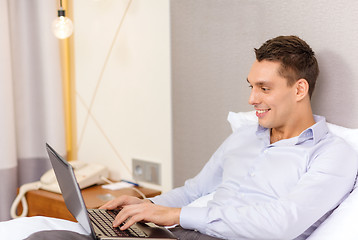 Image showing happy businesswoman with laptop in hotel room