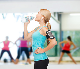 Image showing sporty woman running with smartphone and earphones