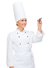 Image showing smiling female chef writing something on air