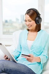 Image showing happy woman with tablet pc and credit card at home