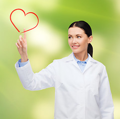 Image showing smiling female doctor pointing to heart