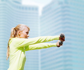 Image showing sporty woman with light dumbbells outdoors