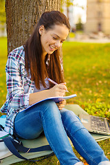 Image showing smiling teenager writing in notebook