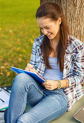 Image showing smiling teenager writing in notebook