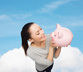 Image showing happy woman looking at piggy bank