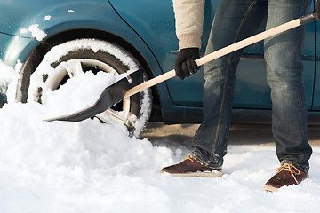 Image showing closeup of man digging up stuck in snow car