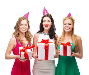 Image showing three smiling women in blue hats with gift boxes