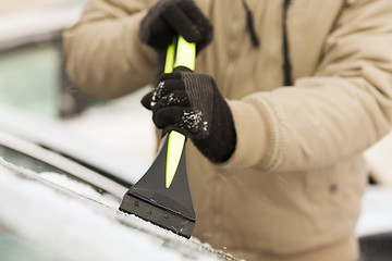 Image showing closeup of man scraping ice from car