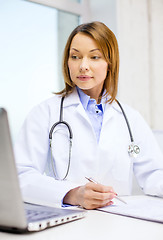 Image showing busy doctor with laptop computer and clipboard