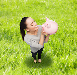 Image showing happy woman looking at piggy bank