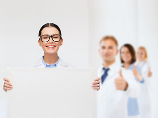 Image showing female doctor in eyeglasses with white blank board