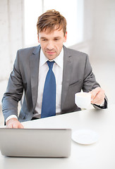 Image showing smiling businessman working with laptop computer