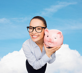 Image showing happy businesswoman in eyeglasses with piggy bank