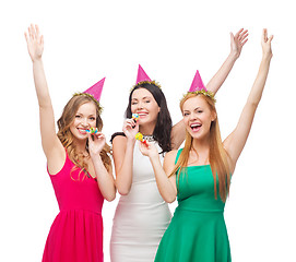 Image showing three smiling women in hats blowing favor horns