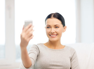 Image showing smiling woman with smartphone at home