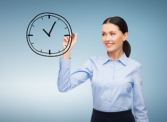 Image showing businesswoman drawing clock in the air