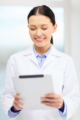 Image showing smiling young doctor with tablet pc in cabinet