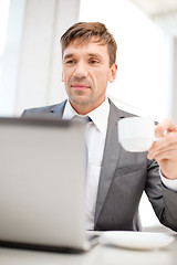 Image showing smiling businessman working with laptop computer