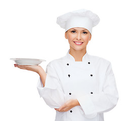 Image showing smiling female chef with empty plate