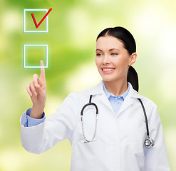 Image showing smiling female doctor pointing to checkbox